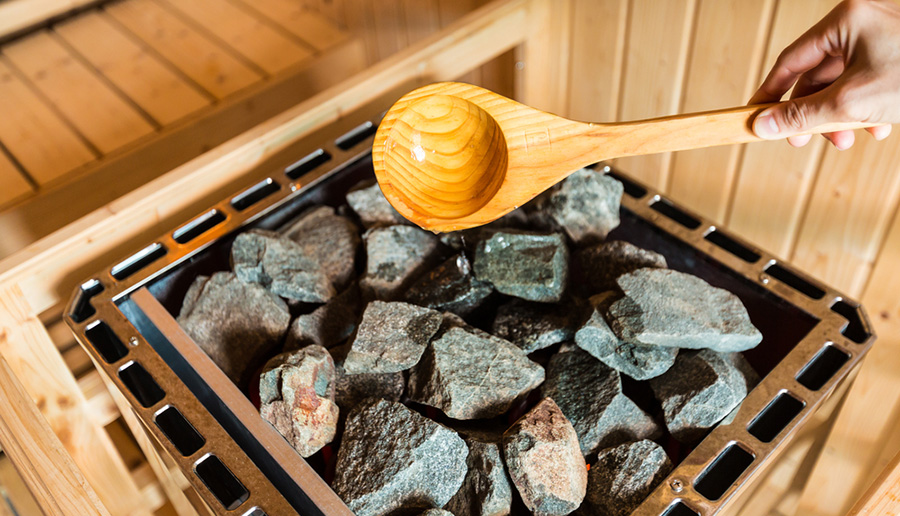 pouring water onto hot stone in sauna